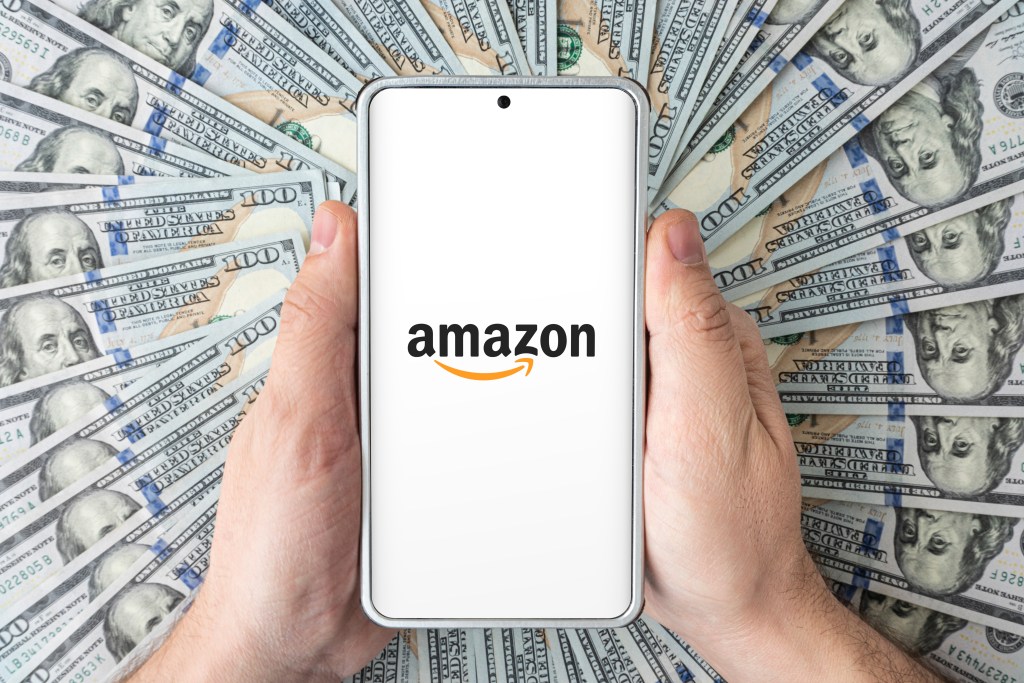 Amazon logo displayed on a cellular device surround by 100 dollar bills. Meant to show the potential revenue from Amazon Local Ads.
